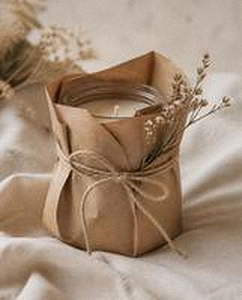 Vela envuelta como regalo en papel kraft con cinta natural y flores secas